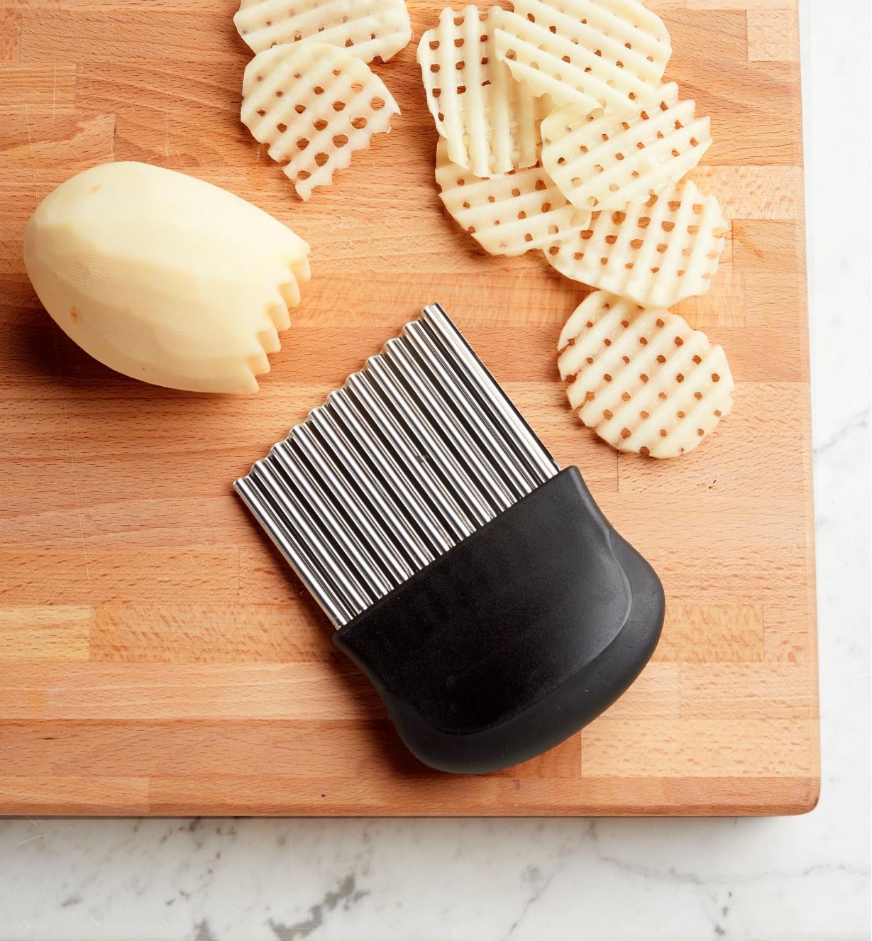 Crinkle Cutter on a cutting board next to potatoes being cut into latticed slices