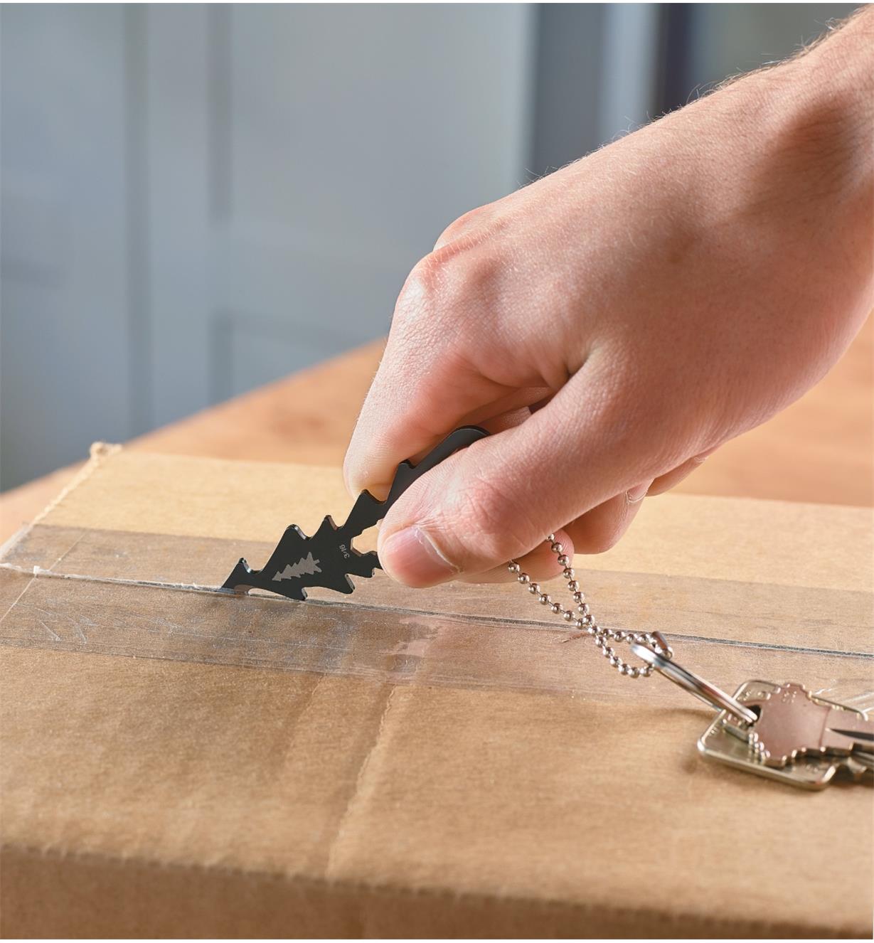 Using the Lee Valley Key-Chain Multi-Tool to cut the tape sealing a cardboard box 