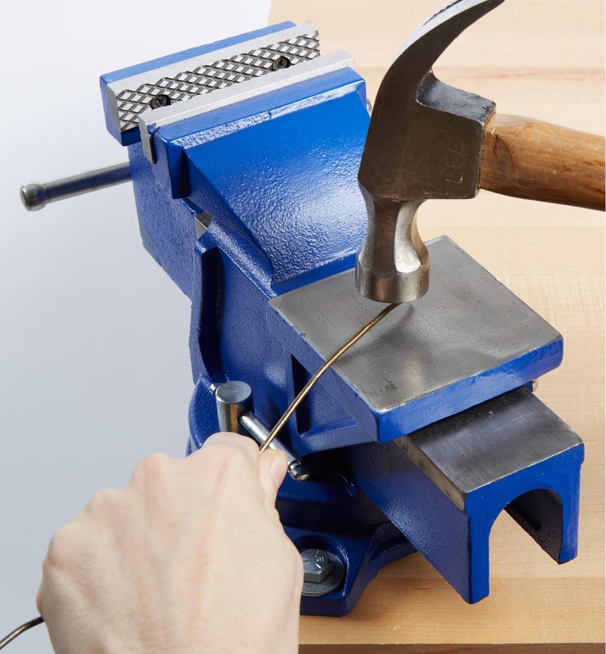 Bending a wire using a hammer against the anvil on the heavy-duty vise