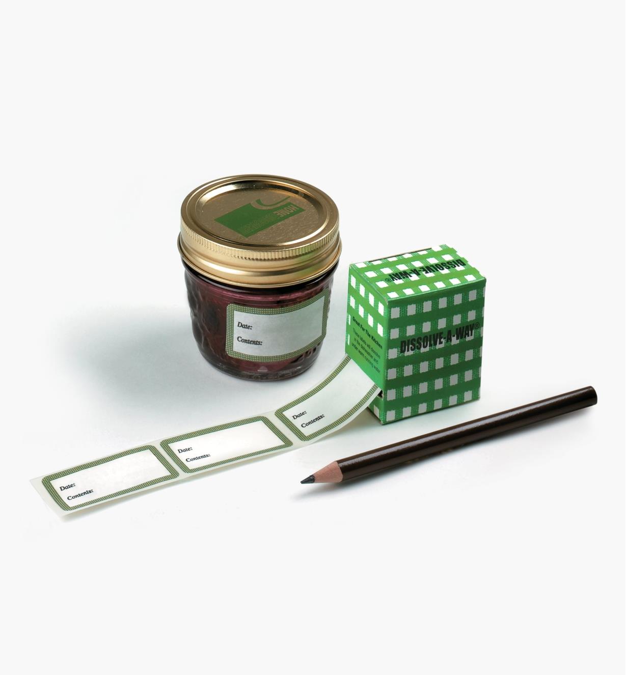 Box of dissolvable labels next to a jam jar and a pencil