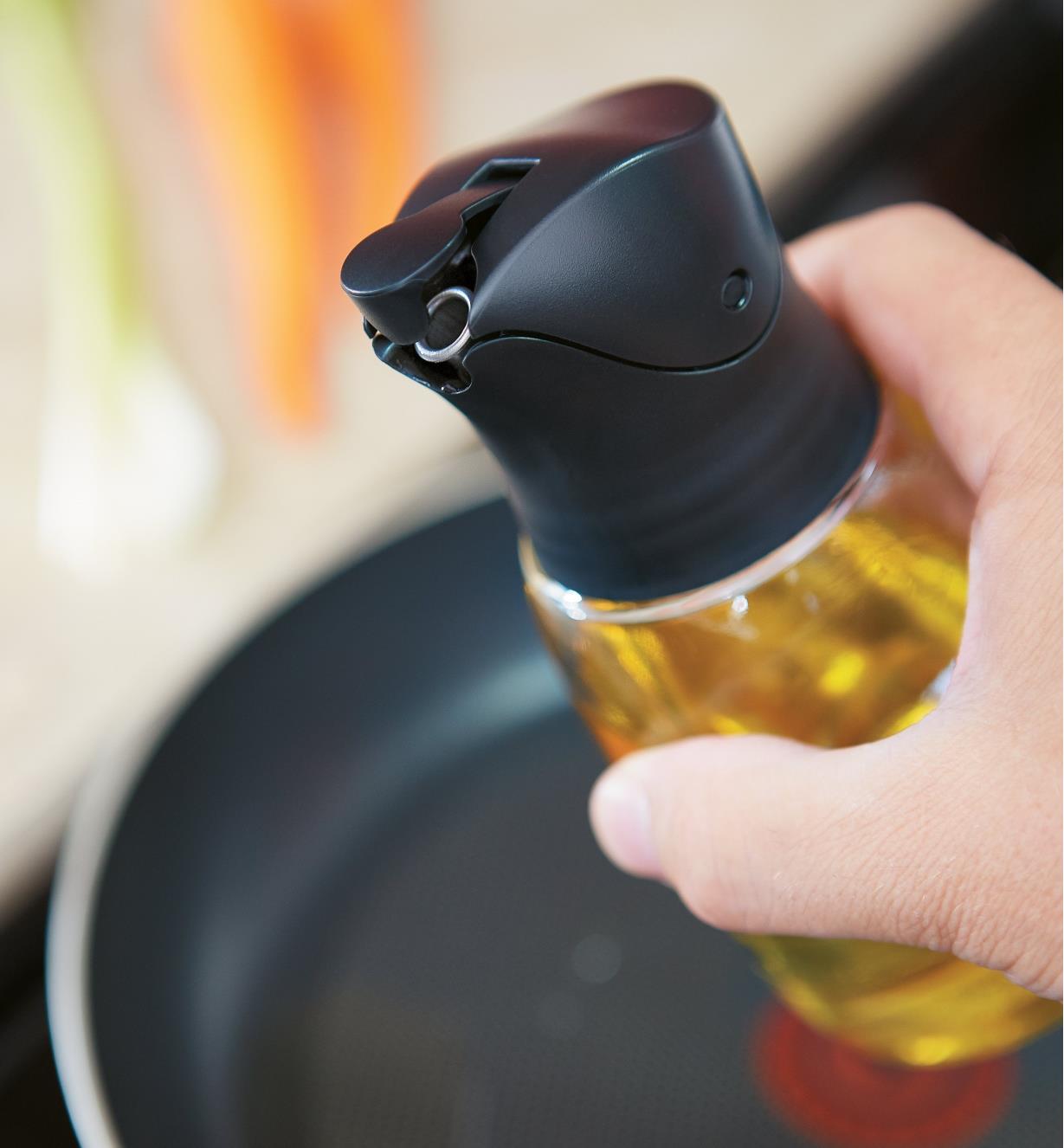 Flip cap opening as bottle is tilted to pour oil into a frying pan