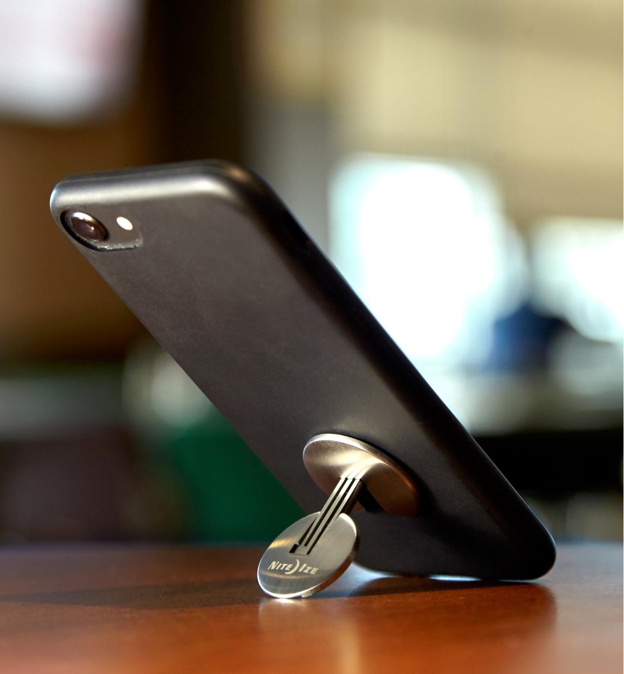 Nite Ize FlipOut Handle & Stand attached to a phone, folded out to prop the phone on a tabletop