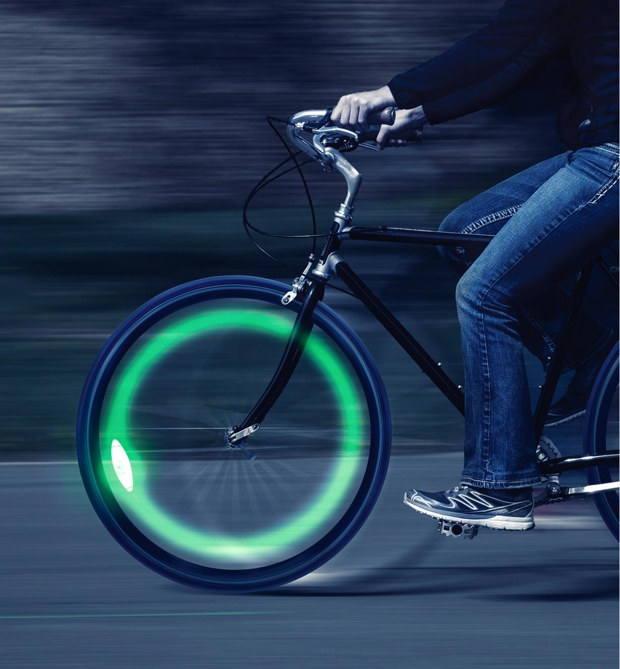 Riding a bicycle at night with a SpokeLit wheel light installed glowing green