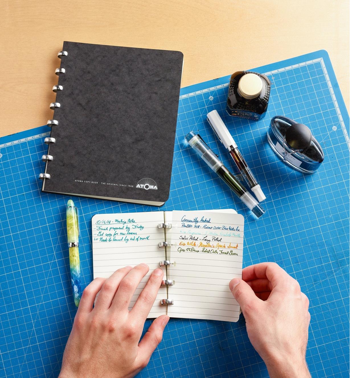 Removing a written-on page from the small Atoma notebook, with the large notebook sitting close by