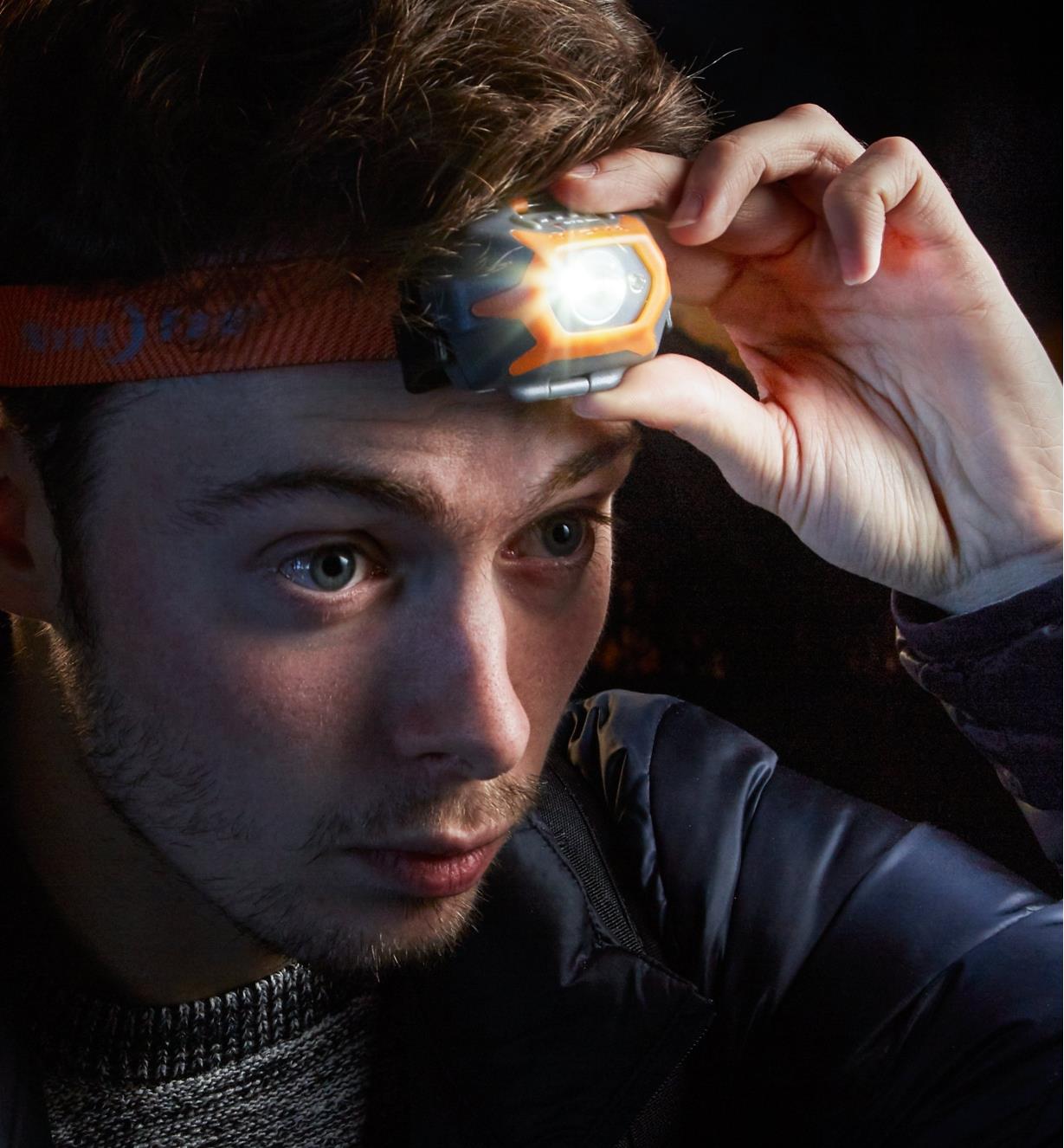 A man wearing a Touch-Activated LED Headlamp, adjusting the brightness