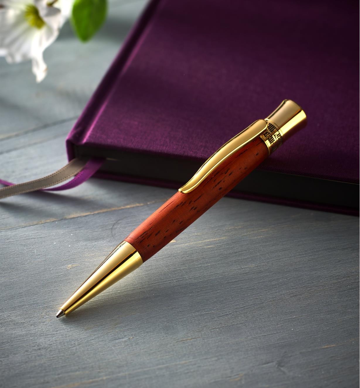 Example of a Glacia gold pen turned from a wood blank, propped on a closed journal 