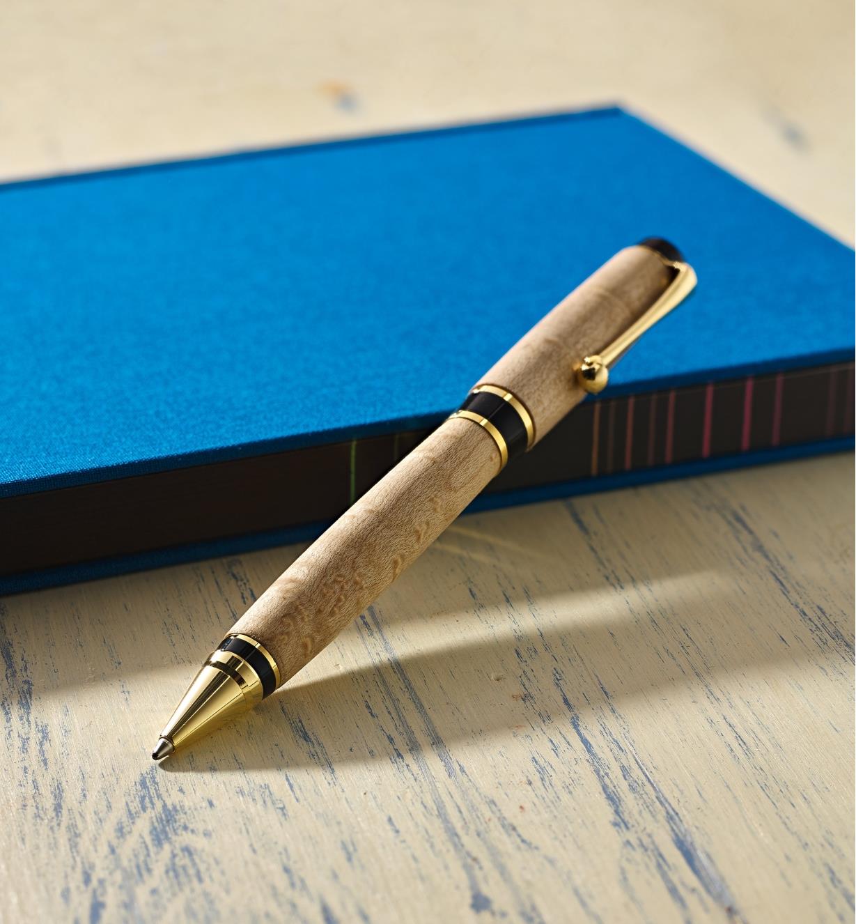 Example of an Olmsted gold pen turned from a wood blank, propped on a notebook