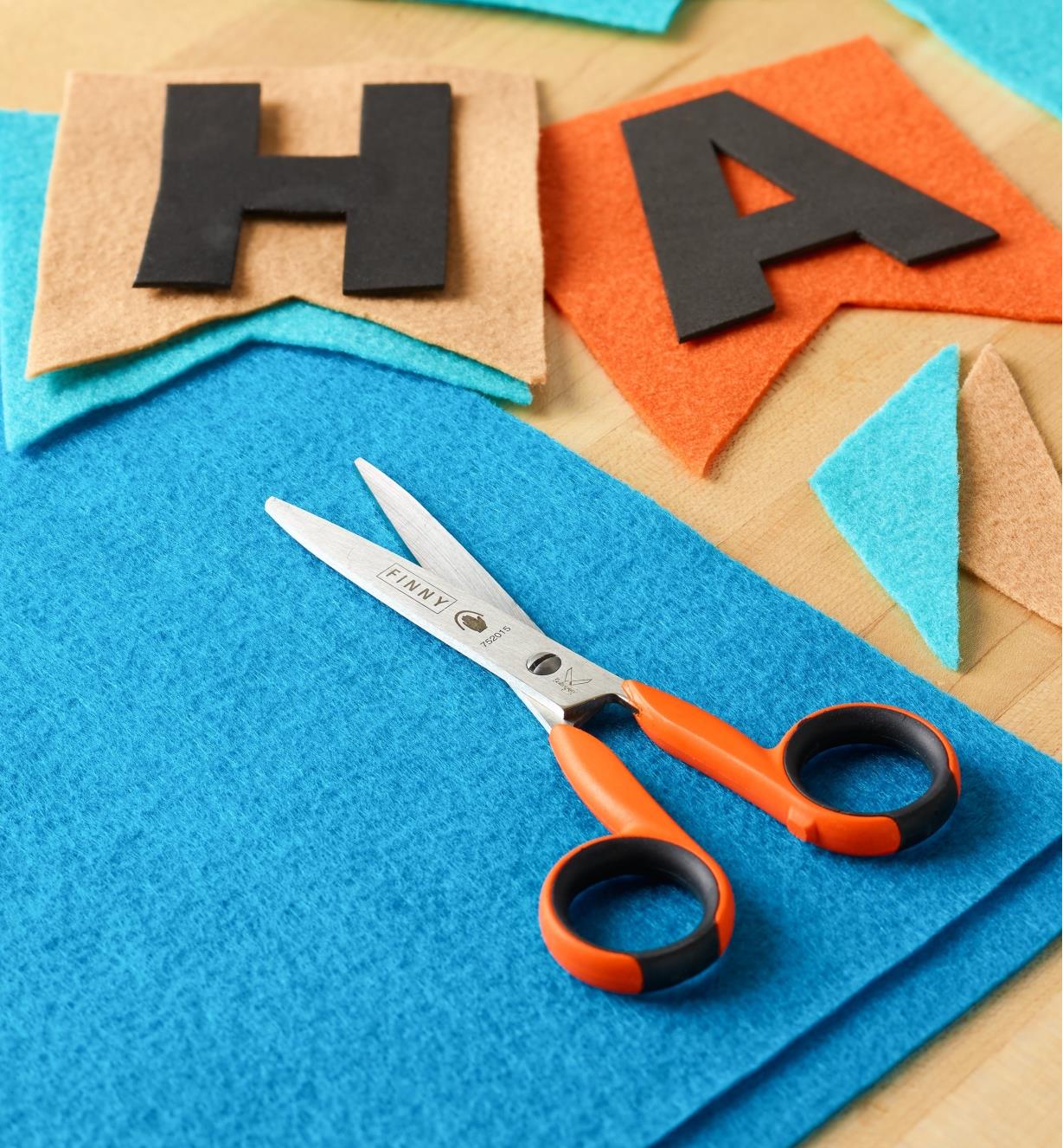 Precision Safety Scissors lying on a piece of felt next to cut-out felt letters