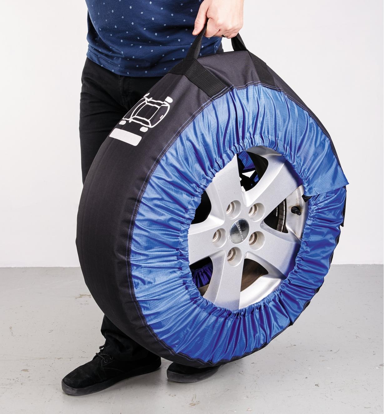 A man carries a tire in a tire bag