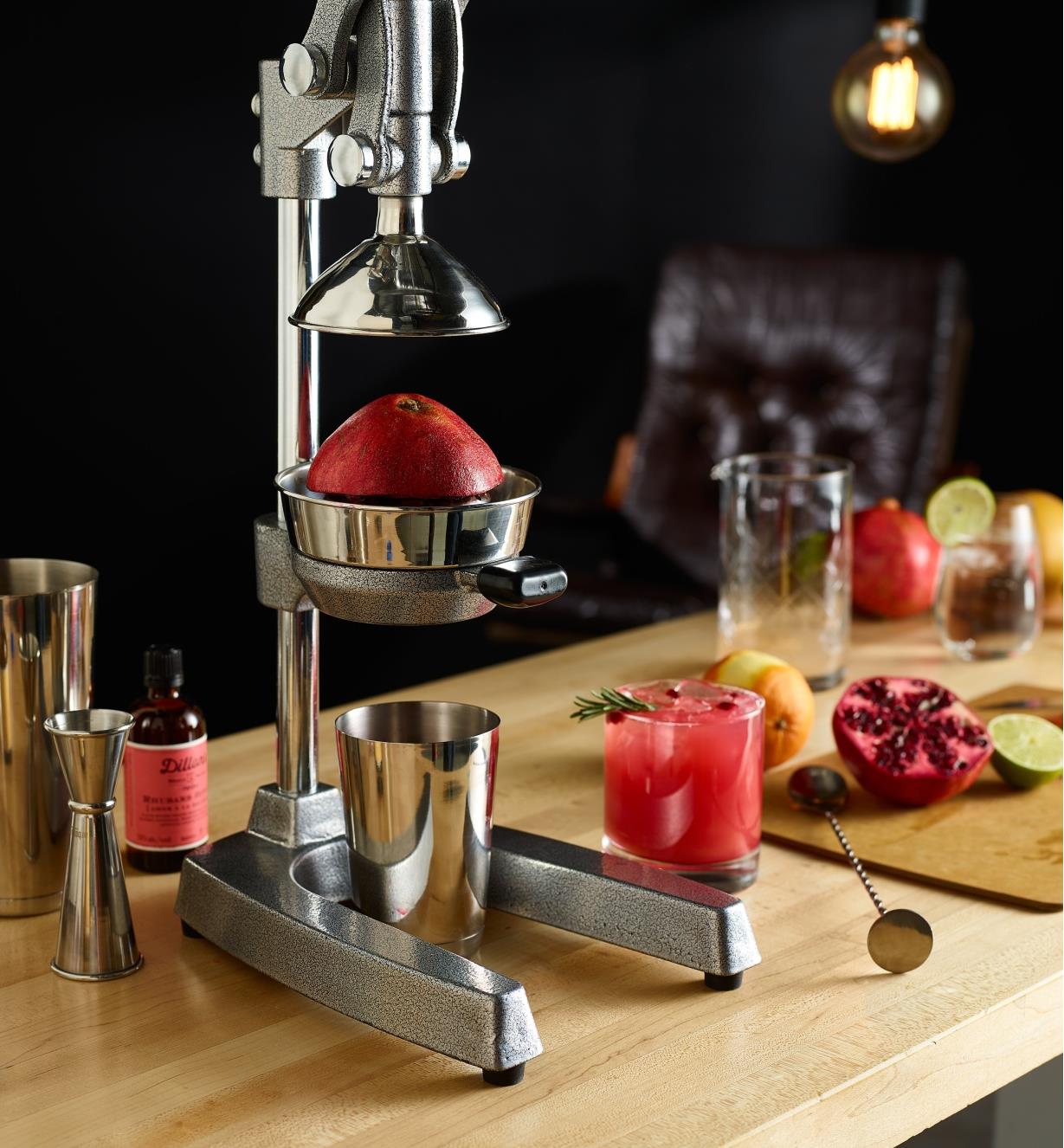 A juice press in a home bar setting, used to squeeze a fresh pomegranate