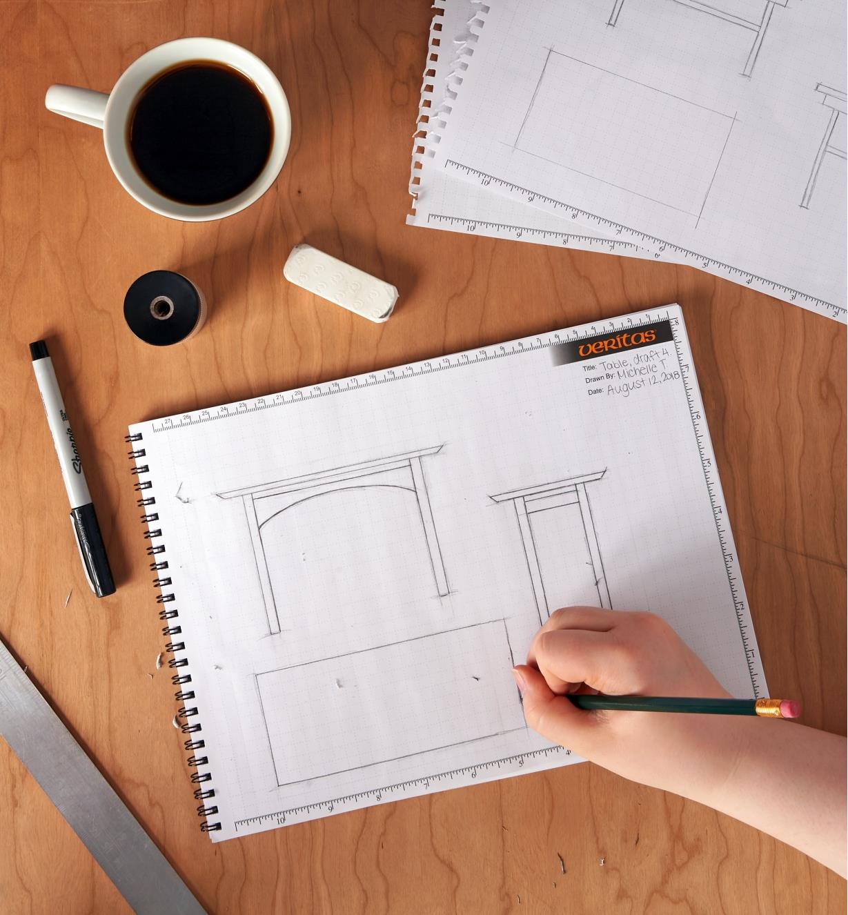 Drawing furniture designs in the spiral-bound workshop design pad.