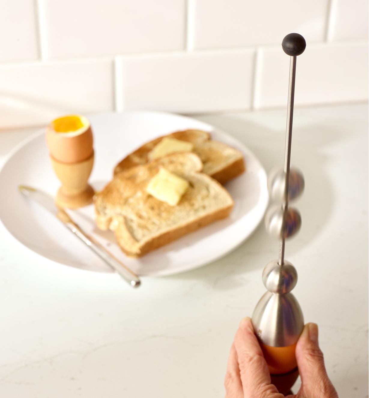 The weight of the Clack Soft-Boiled Egg Topper dropping to crack an egg