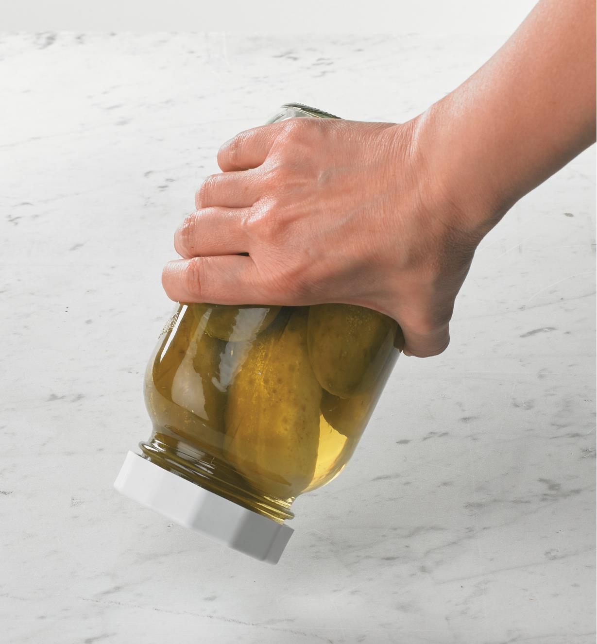 A canning jar lid on a jar of pickles held upside down