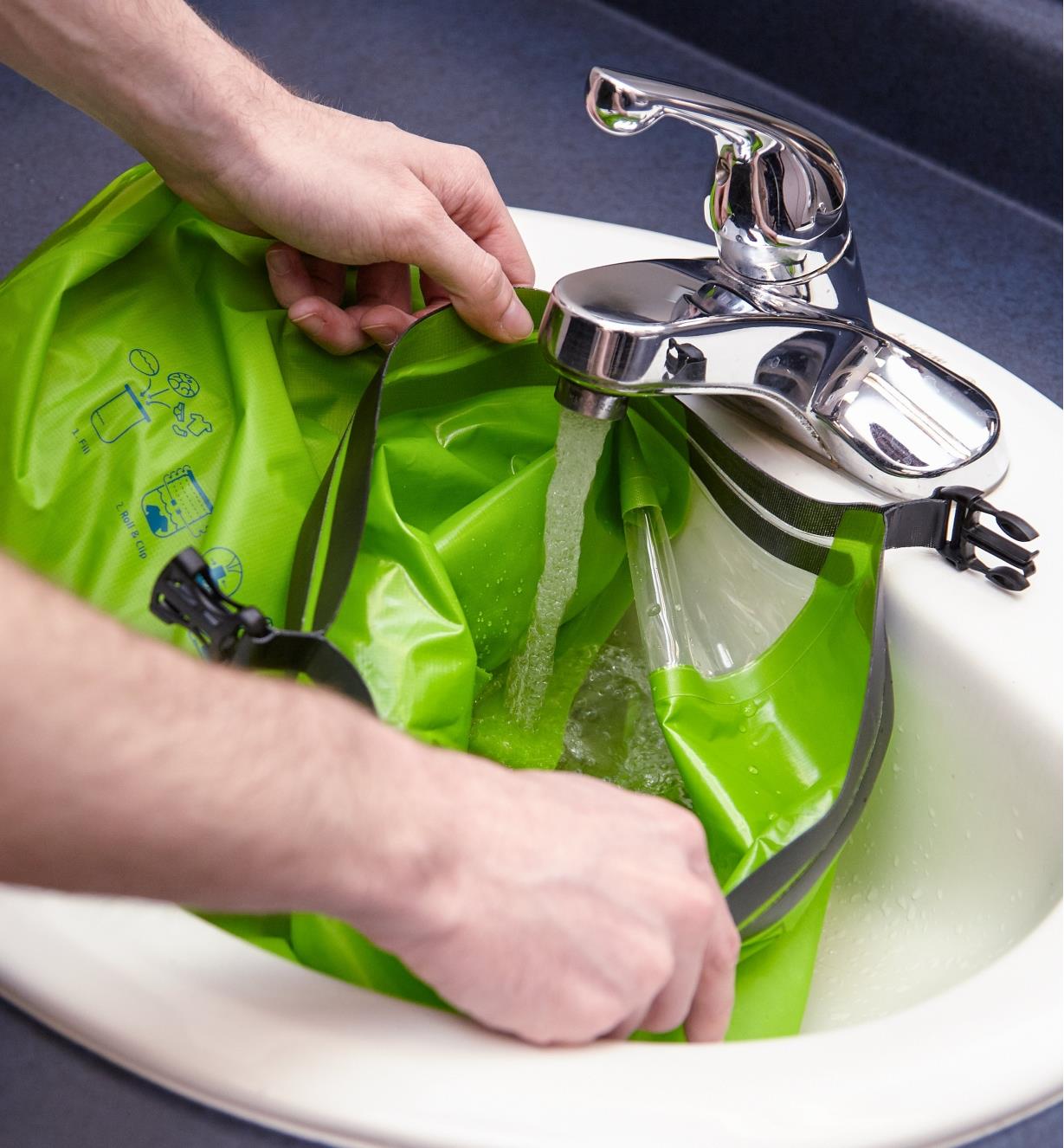 Personne rinçant un sac lave-linge Scrubba sous un robinet