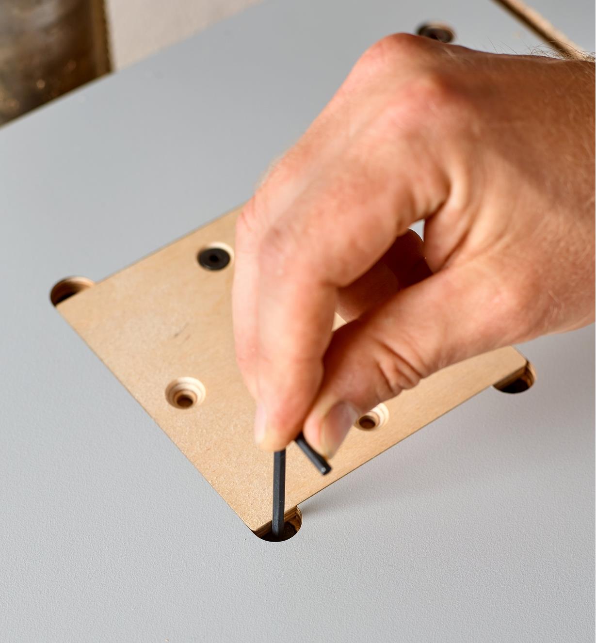Using built-in levelling screws to set the wooden insert flush with the drill-press table surface