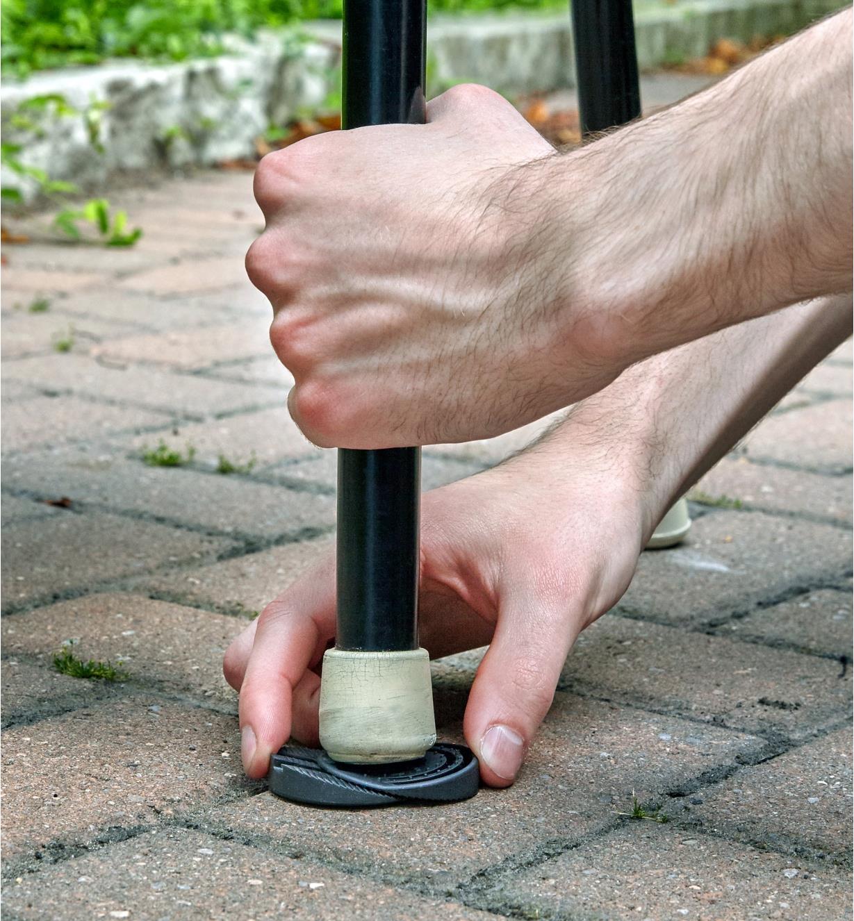 Wedging the adjustable furniture leveller under the leg of a patio chair