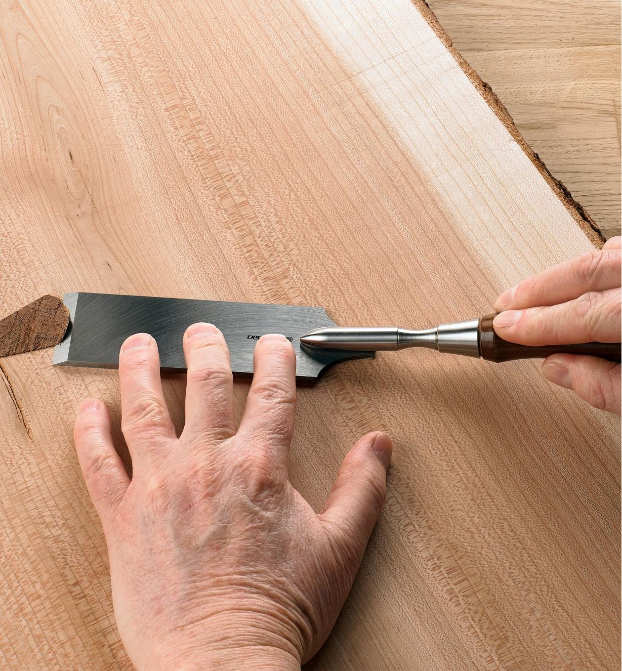 A man uses a Veritas flushing chisel to flush trim a large plank of wood