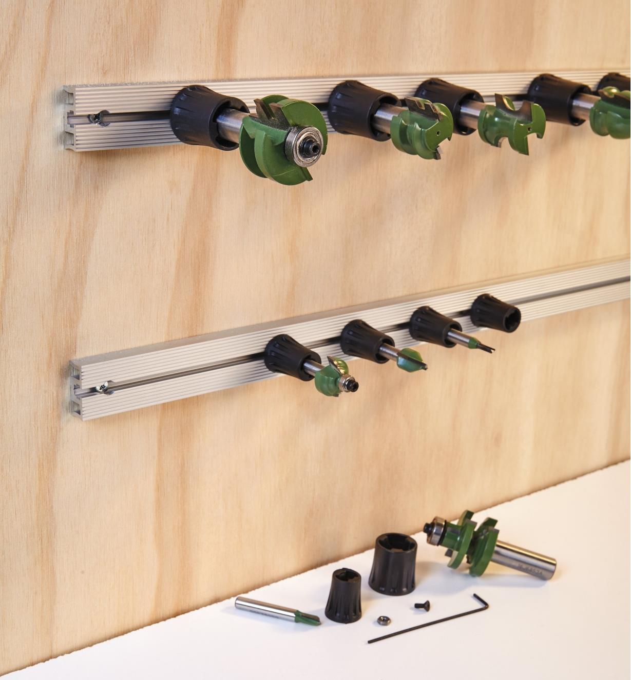 Two tracks including router bits in holders mounted horizontally on a wall