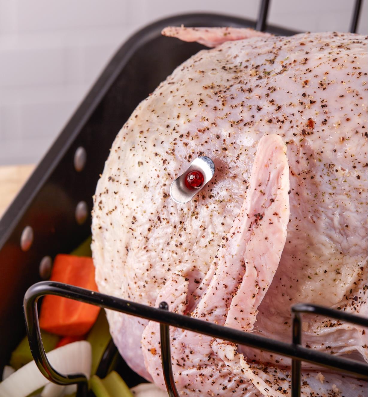 The reusable pop-up turkey timer is inserted in the thickest part of the breast of an uncooked turkey