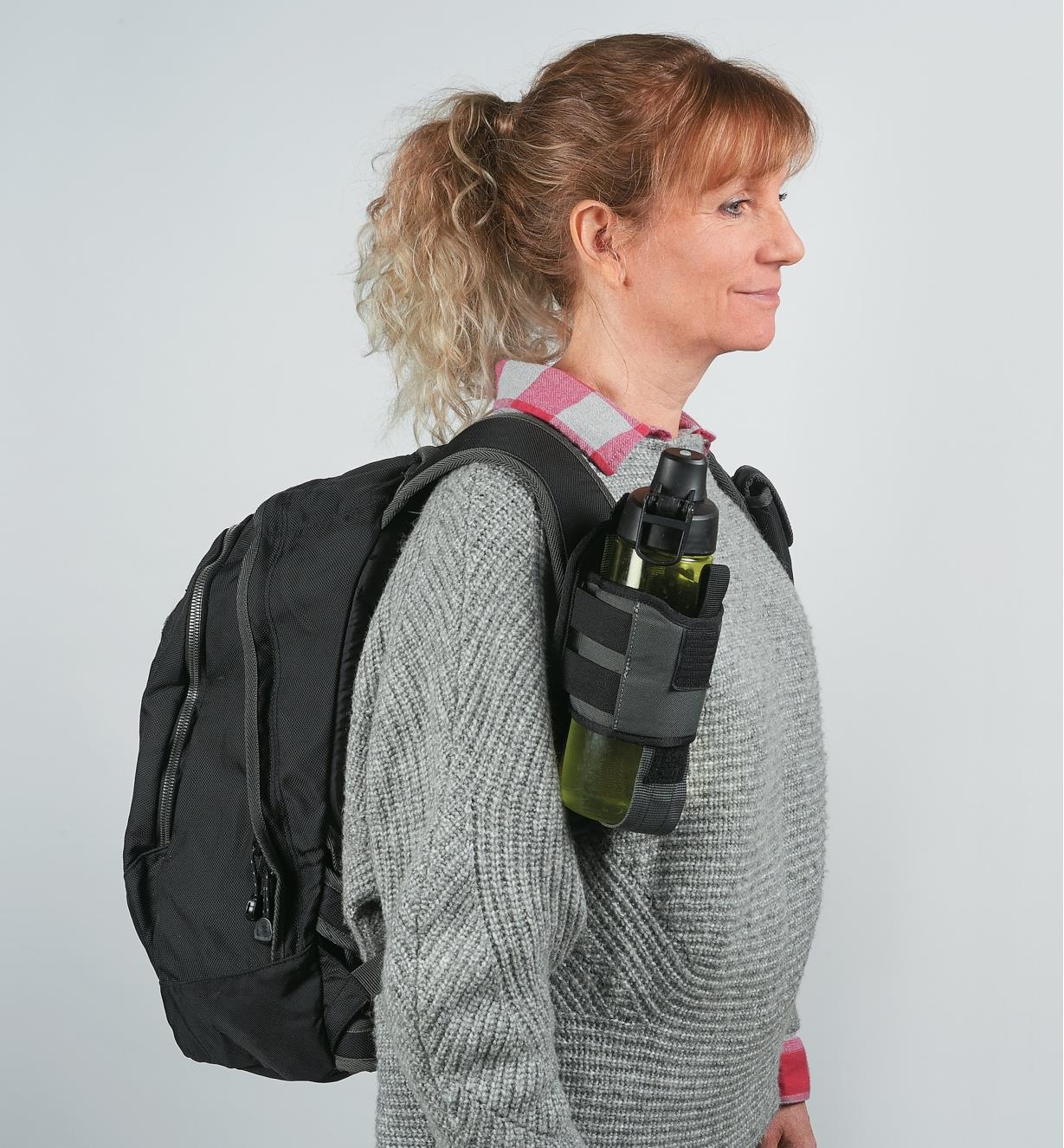 A woman wearing a backpack with a Drink Holster attached