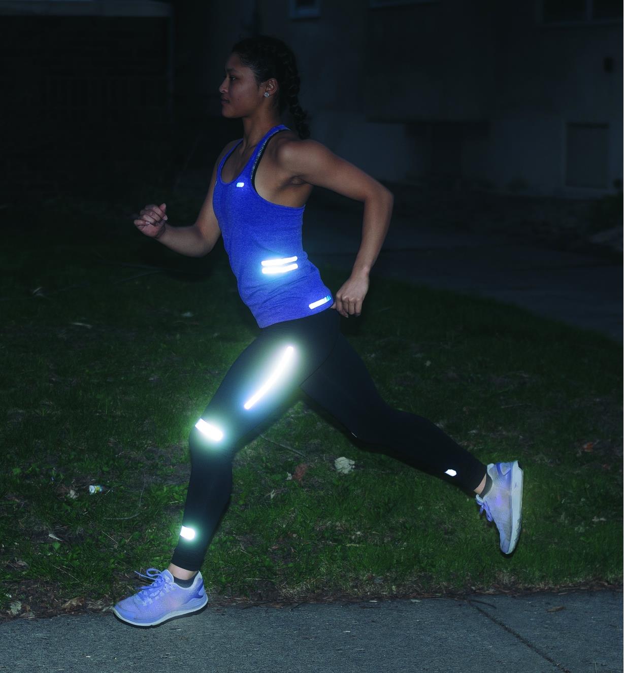 A woman running at night with Iron-On & Peel-and-Stick Reflective Strips applied to her clothing