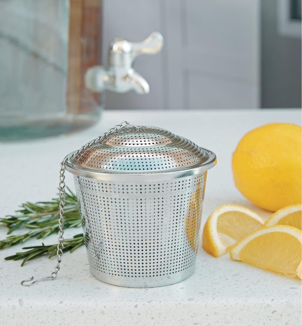 Large Infuser Basket on a counter beside orange slices and rosemary
