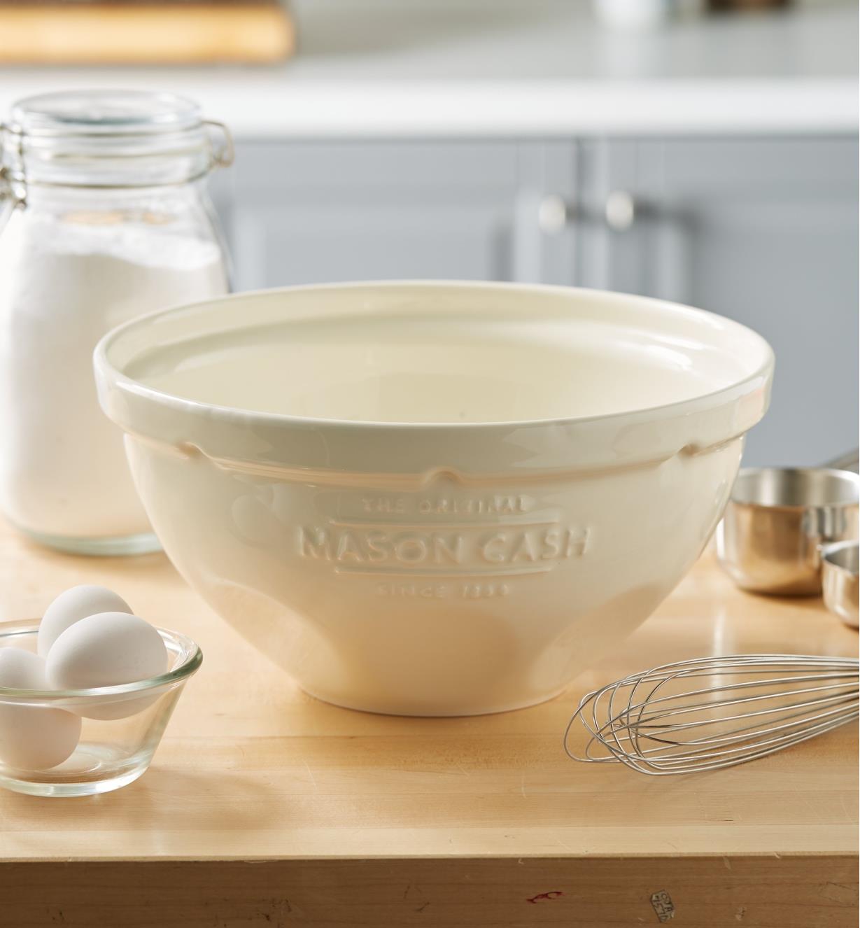 A Mason Cash mixing bowl sits on a kitchen countertop near utensils and ingredients