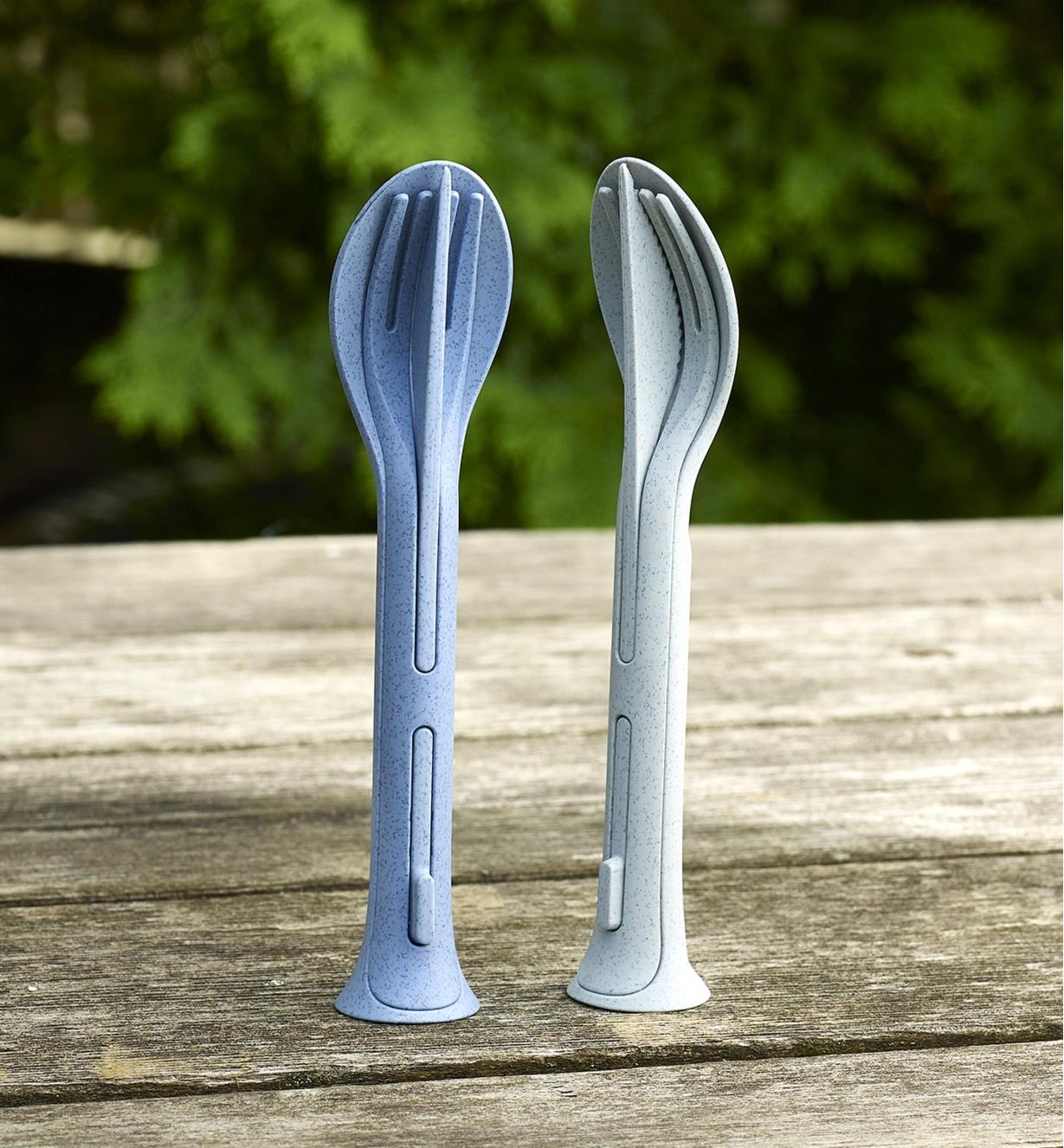 Blue and gray Klikk small cutlery sets standing upright on a picnic table