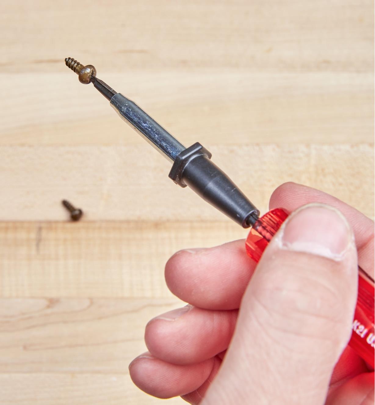 A brass screw held on the tip of the slotted screw-holding screwdriver