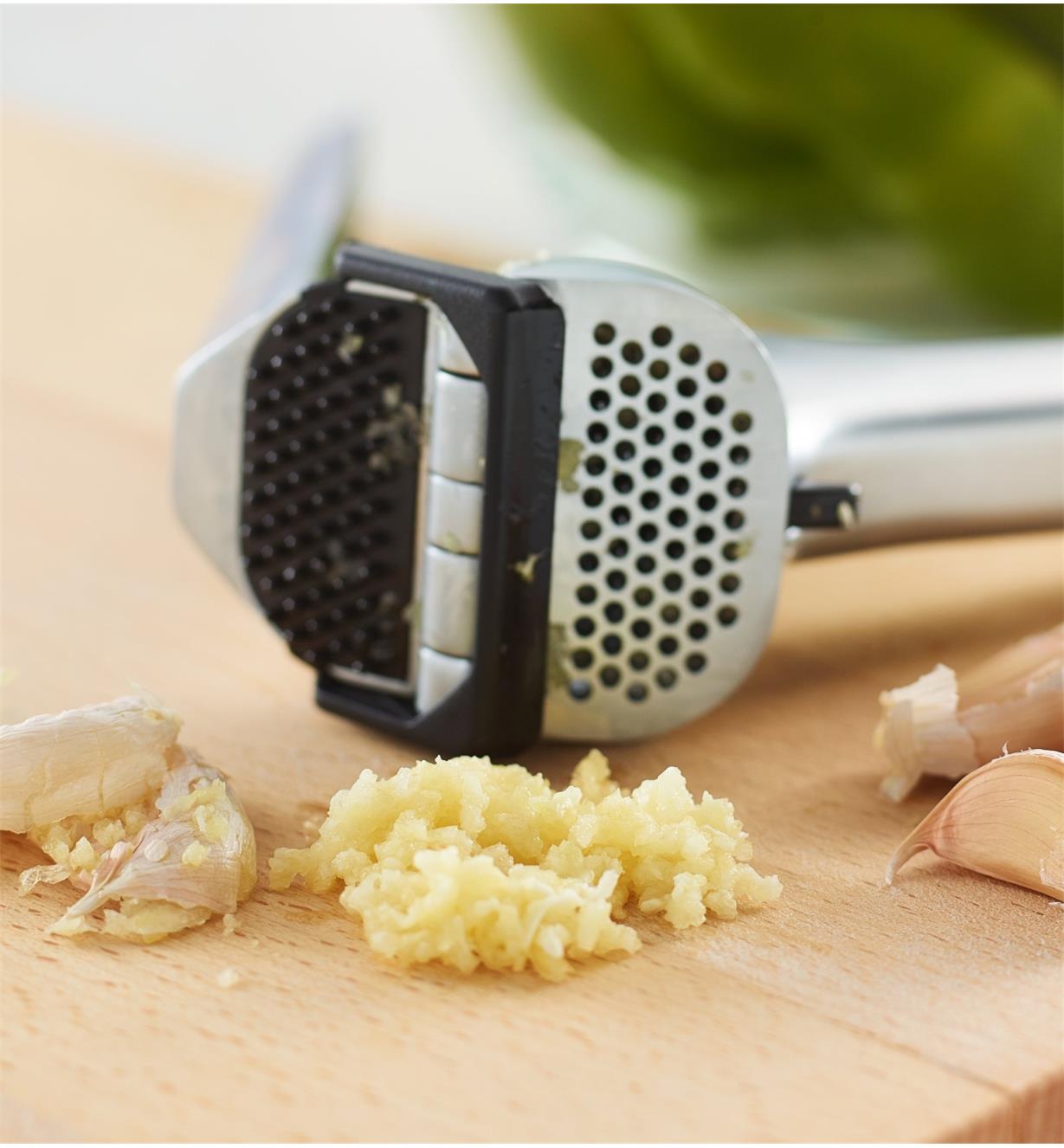Crushed garlic and peel on a cutting board with the Garject Garlic Press