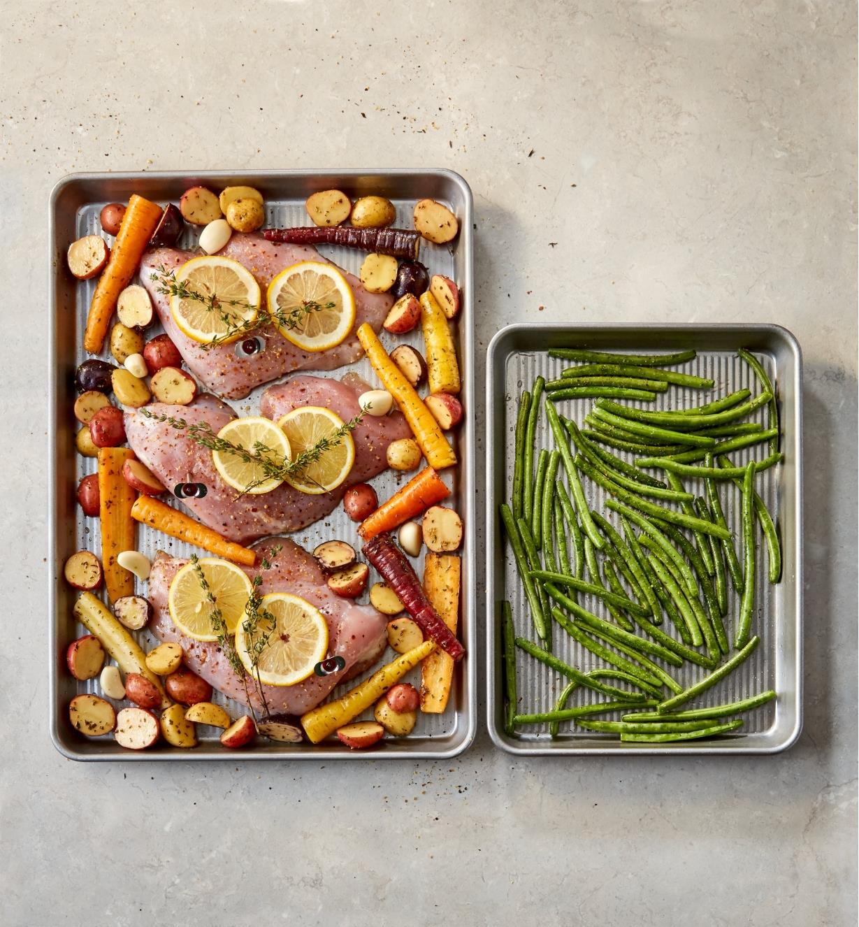 Large baking pan holding salmon and vegetables and small baking pan holding green beans