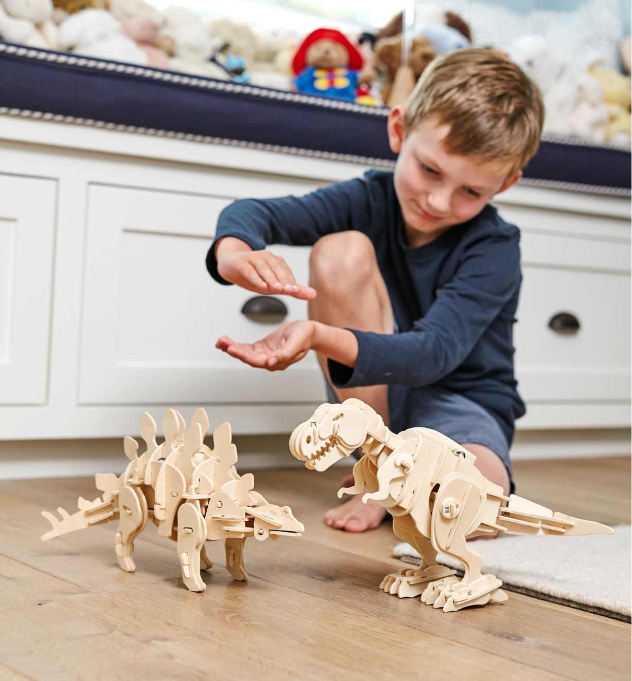 A boy claps his hands to activate the assembled walking dinosaur models