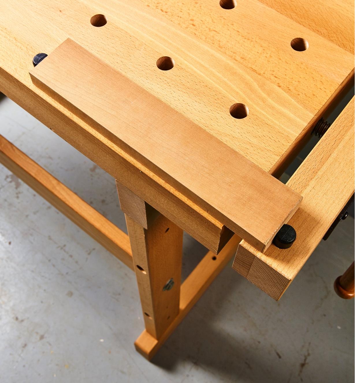 A block of wood clamped using dog holes in the vise and bench top