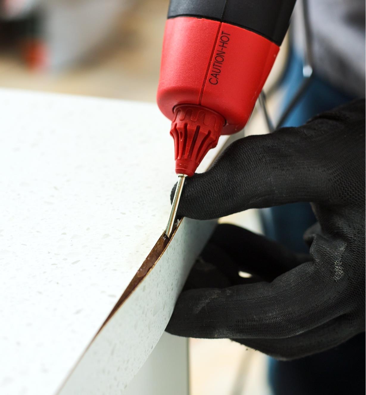Using the FastenMaster pro hot-melt gun repair nozzle to inject glue under a section of lifted edge trim