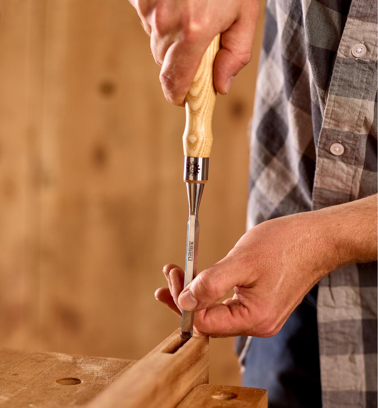 A woodworker uses a 3/8" Narex Richter chisel to smooth the walls of a mortise