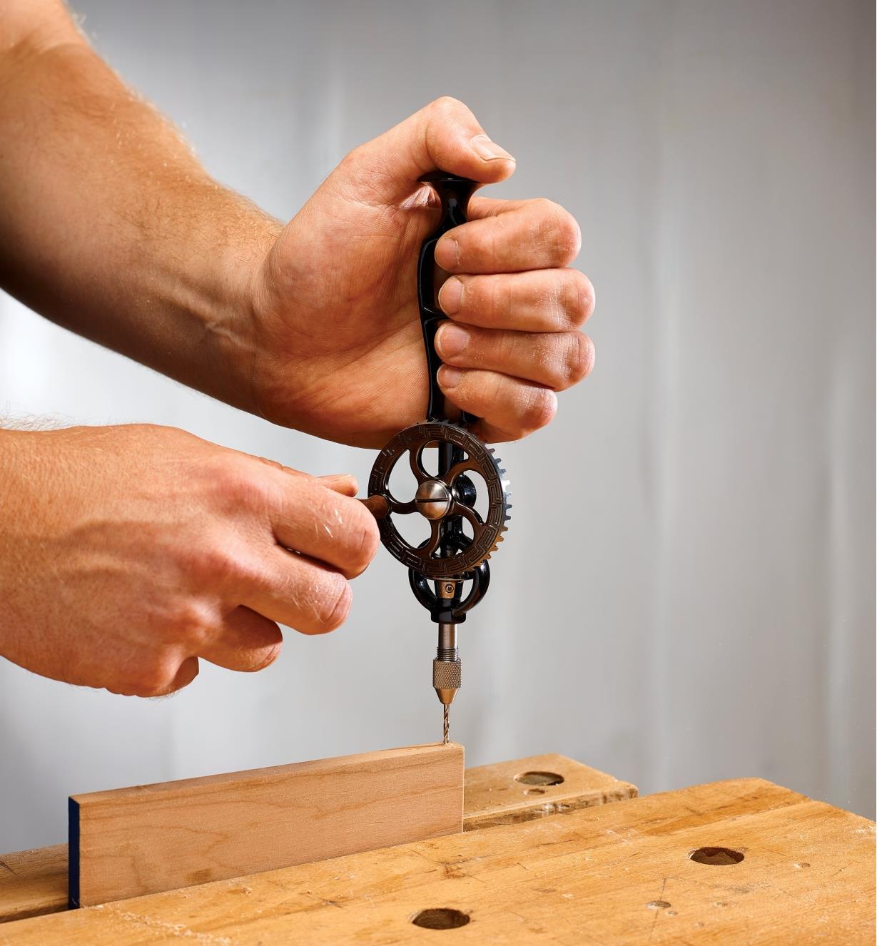 Drilling a hole in the edge of a board with the replica egg-beater drill