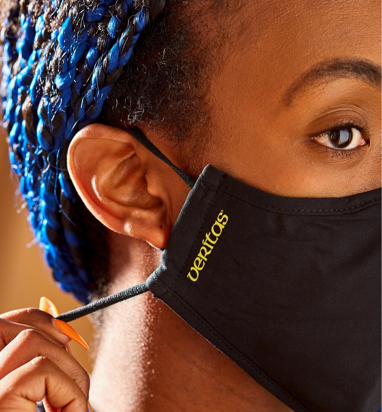 A side view of a woman wearing a Veritas face mask, showing the adjustable ear band