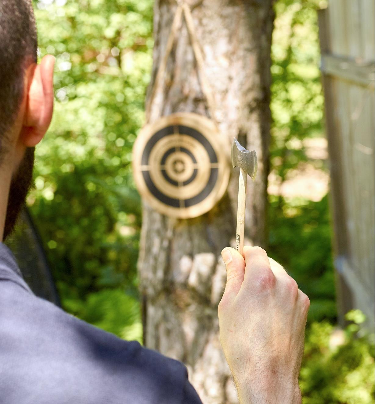 A man playing the mini axe throwing game takes aim at the wooden target