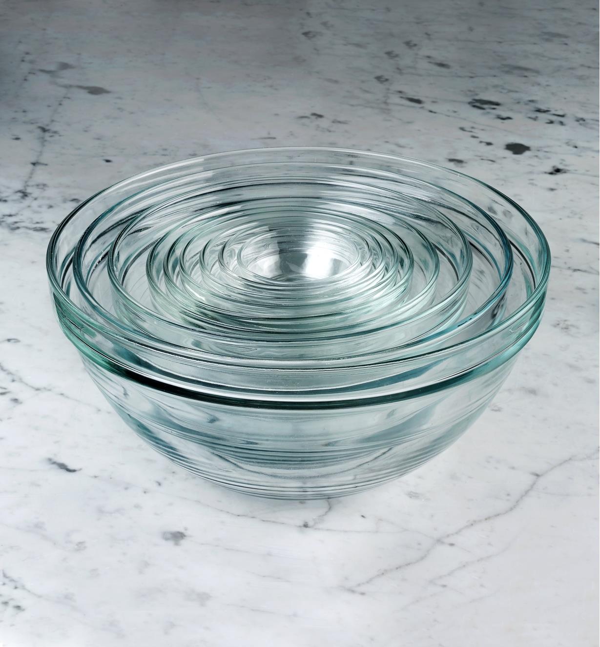 A set of nine Duralex glass bowls sitting on a countertop, nested for compact storage