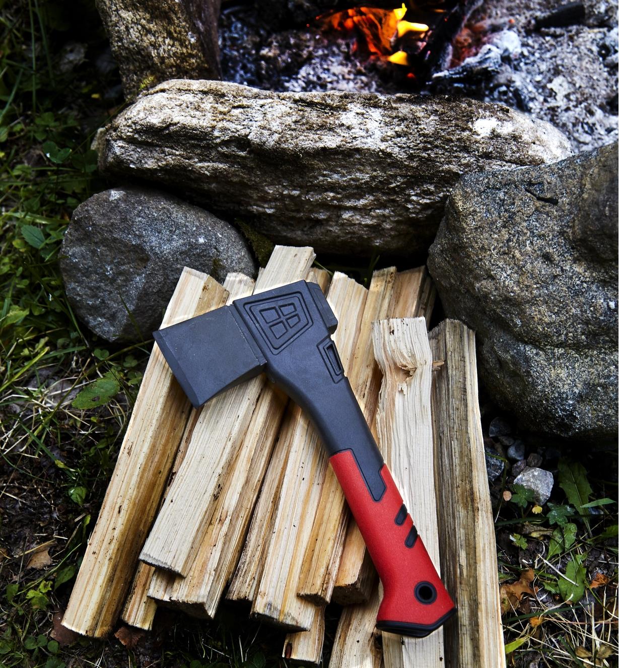 The hatchet lying on a pile of kindling beside a campfire
