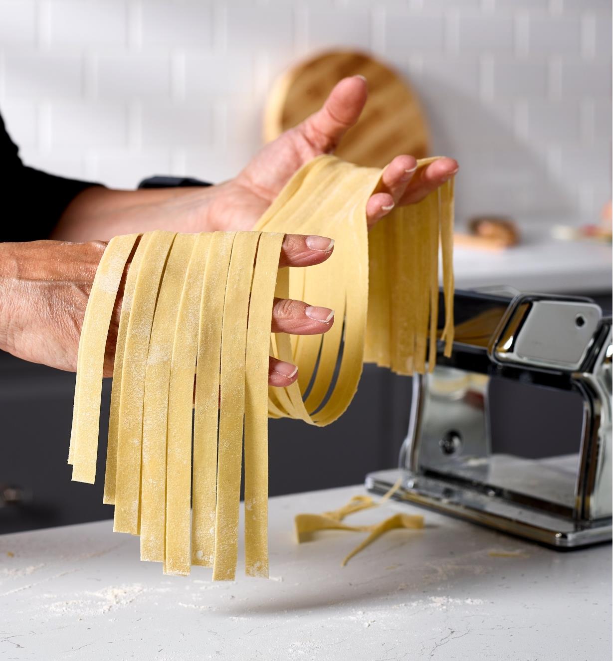 A cook holds lasagnette noodles made with a Marcato pasta machine and a lasagnette cutter attachment