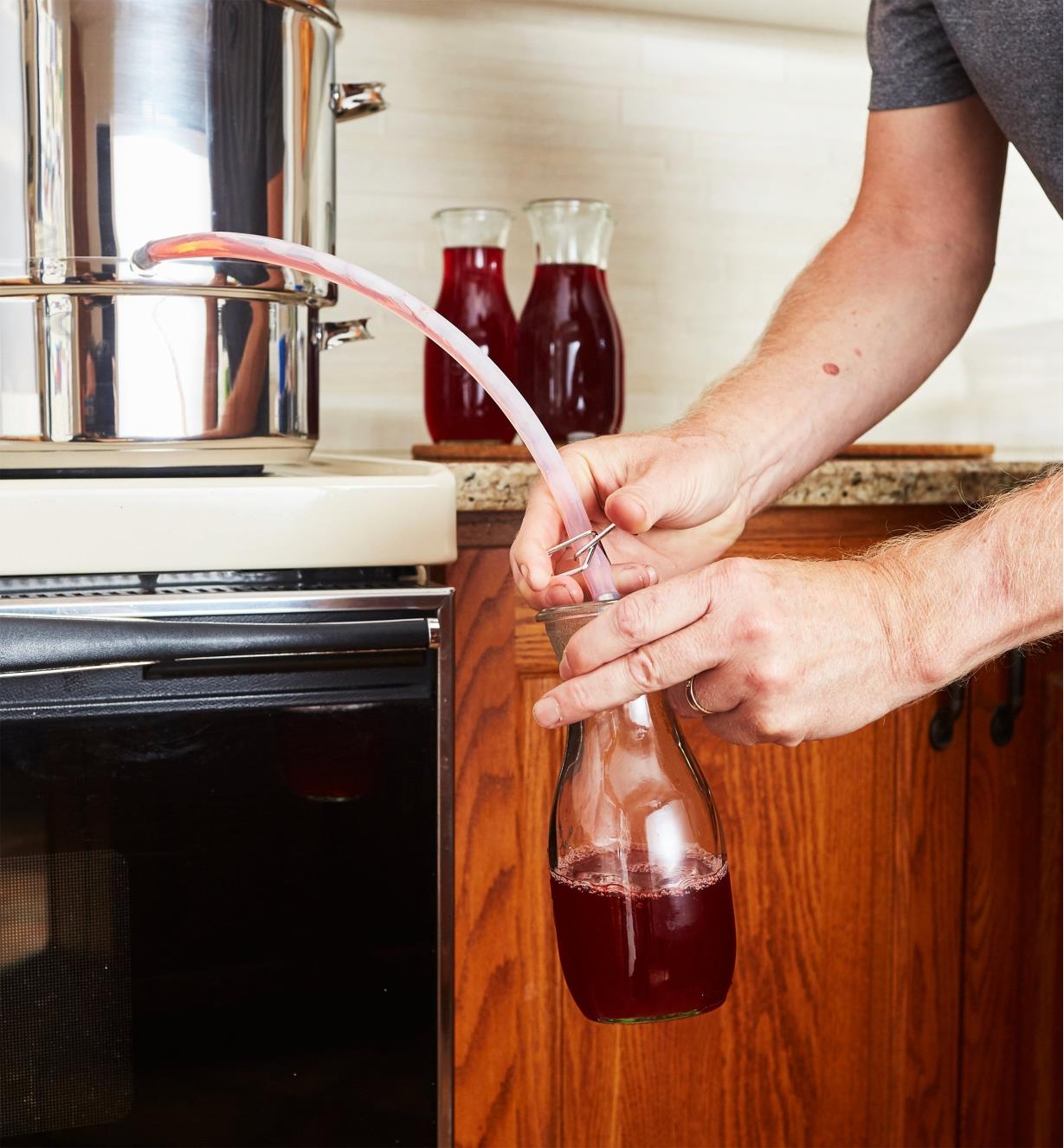 Juice being poured through a hose from a juicer into a glass bottle