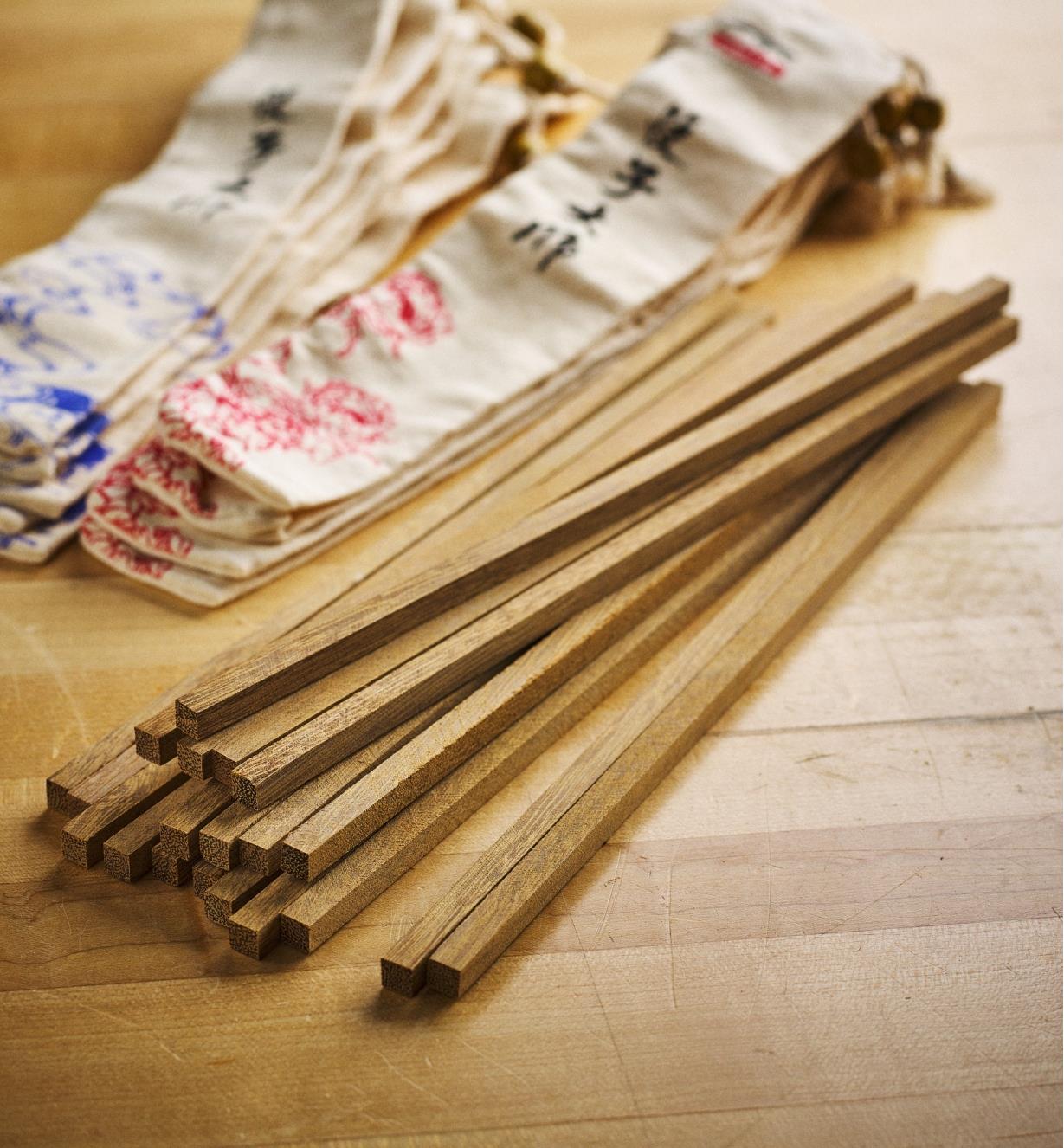 Pile of 10 wenge chopstick blanks with bags in the background