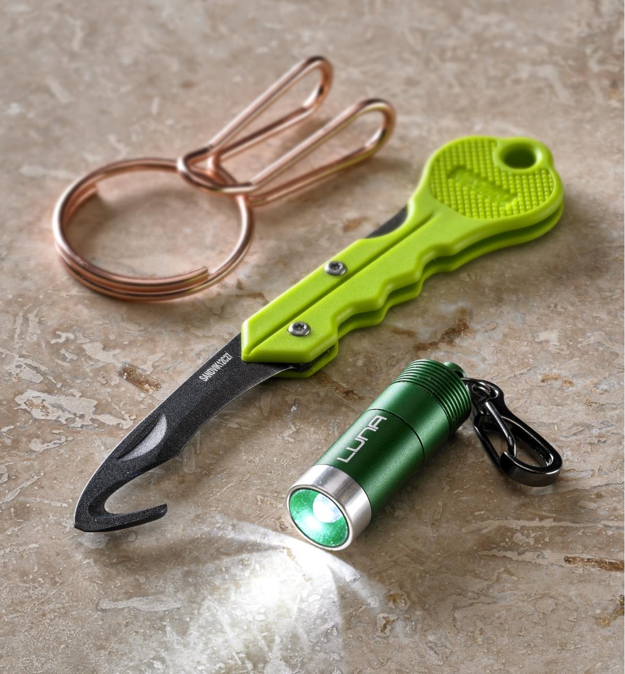 A mini LED clip light, a SqueezeRing key clip and a keychain safety cutter shown together