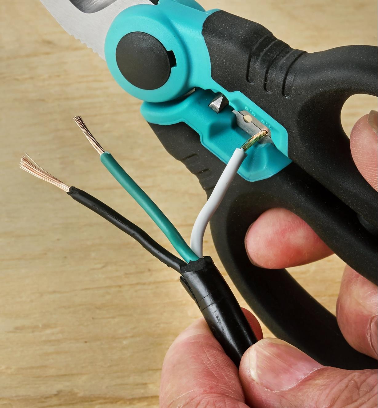 Using the wire-stripping notch of the electrician scissors to remove wire sheathing