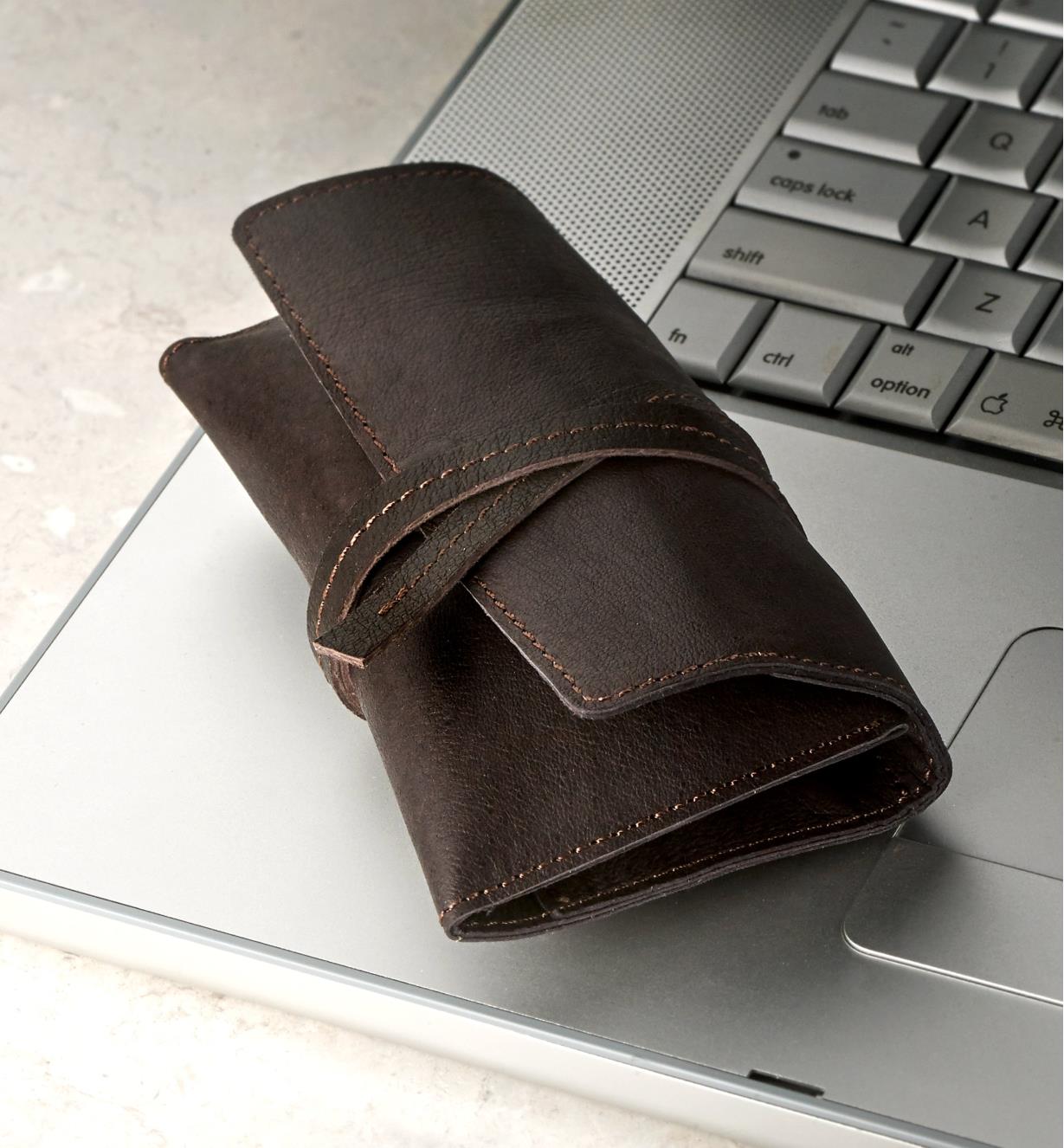 A leather cord wallet on a laptop computer, cinched closed with its leather tie