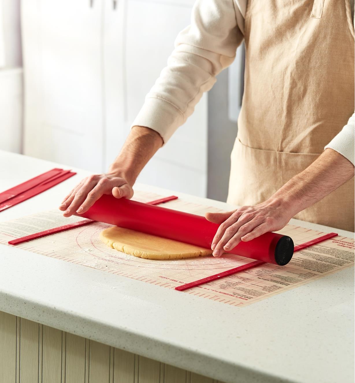 Rolling dough with the rolling pin on the dough mat between thickness guides
