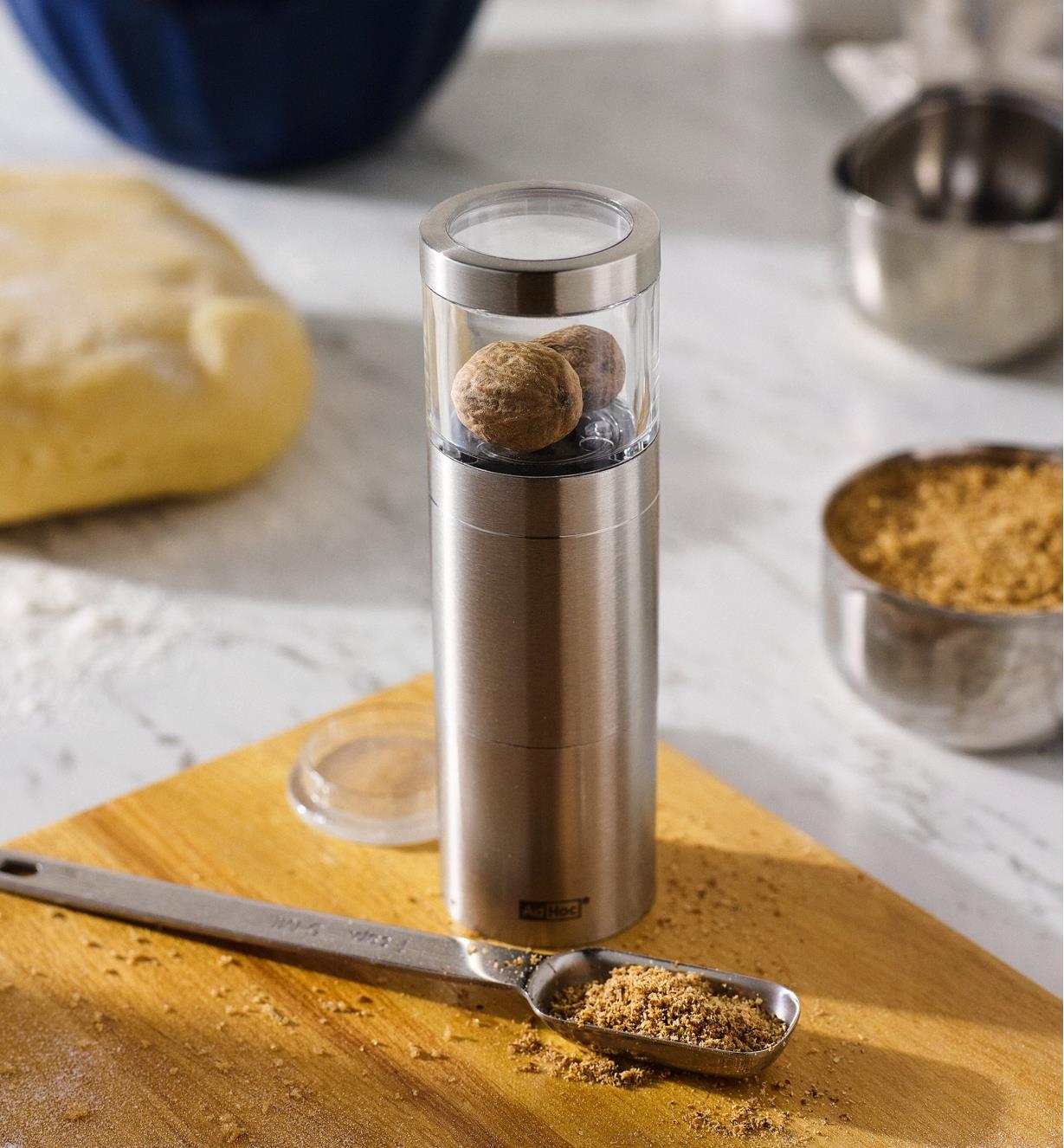 Nutmeg grinder on a cutting board with a measuring spoon of ground nutmeg