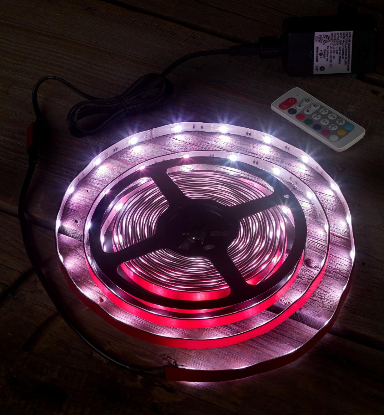 An LED color-controlled tape light kit set to a pale pink-purple hue to test it before installation