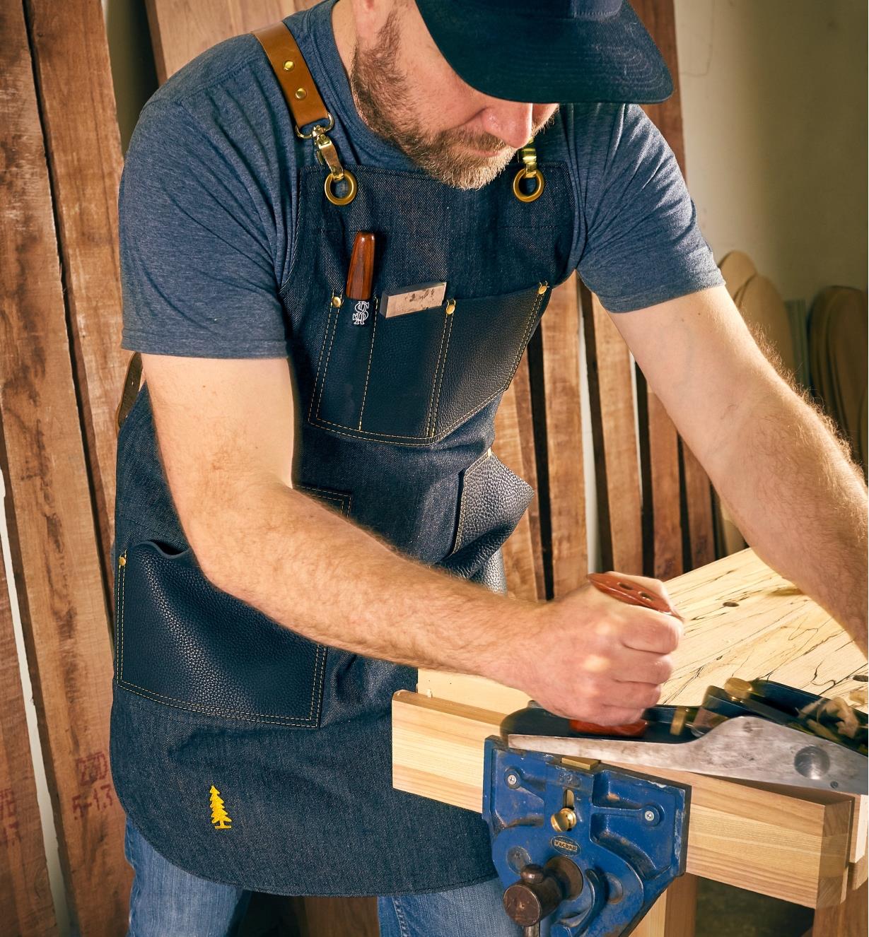 A man planing a board while wearing the All-Purpose Apron